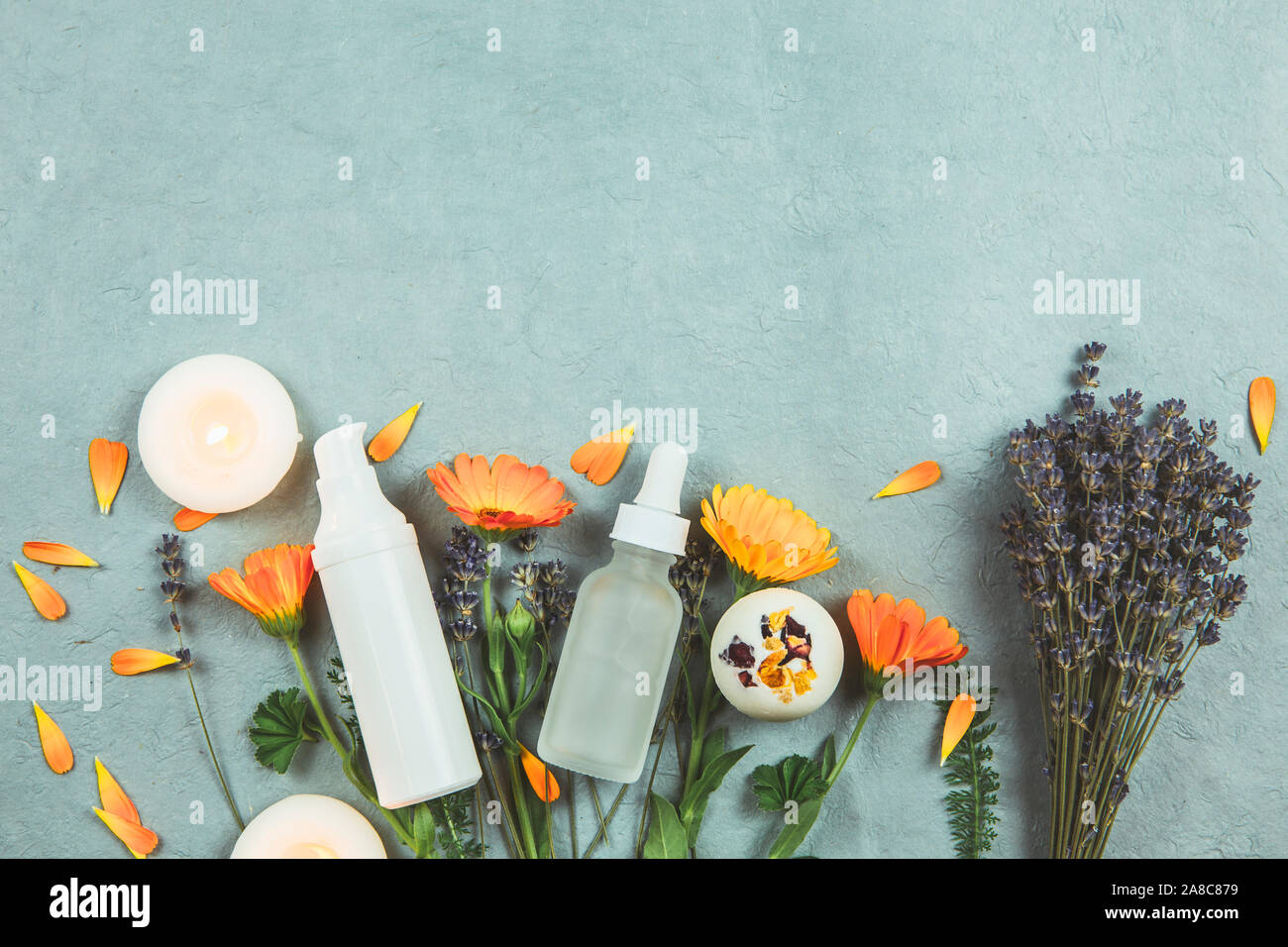 Organici vegetali cosmetici a base di concetto. Vista dall'alto di erbe varie piante e bellezza contenitori per prodotti vintage su sfondo blu. Foto Stock