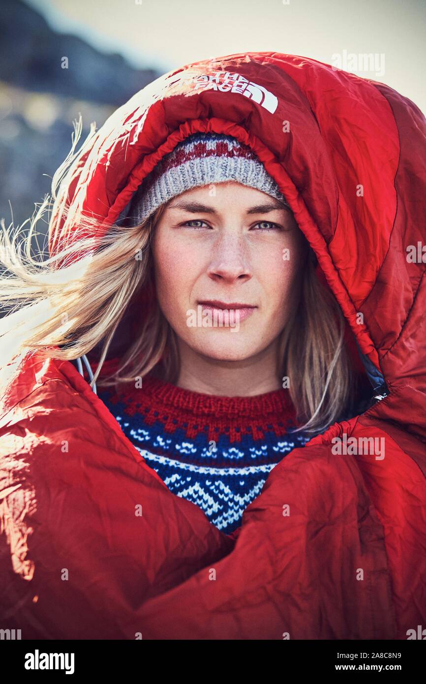 Ritratto di una giovane donna in un rosso sacco a pelo guardando nella telecamera, natura, lo stile di vita di campeggio, outdoor lifestyle, Prekestolen, Rogaland, Norvegia Foto Stock