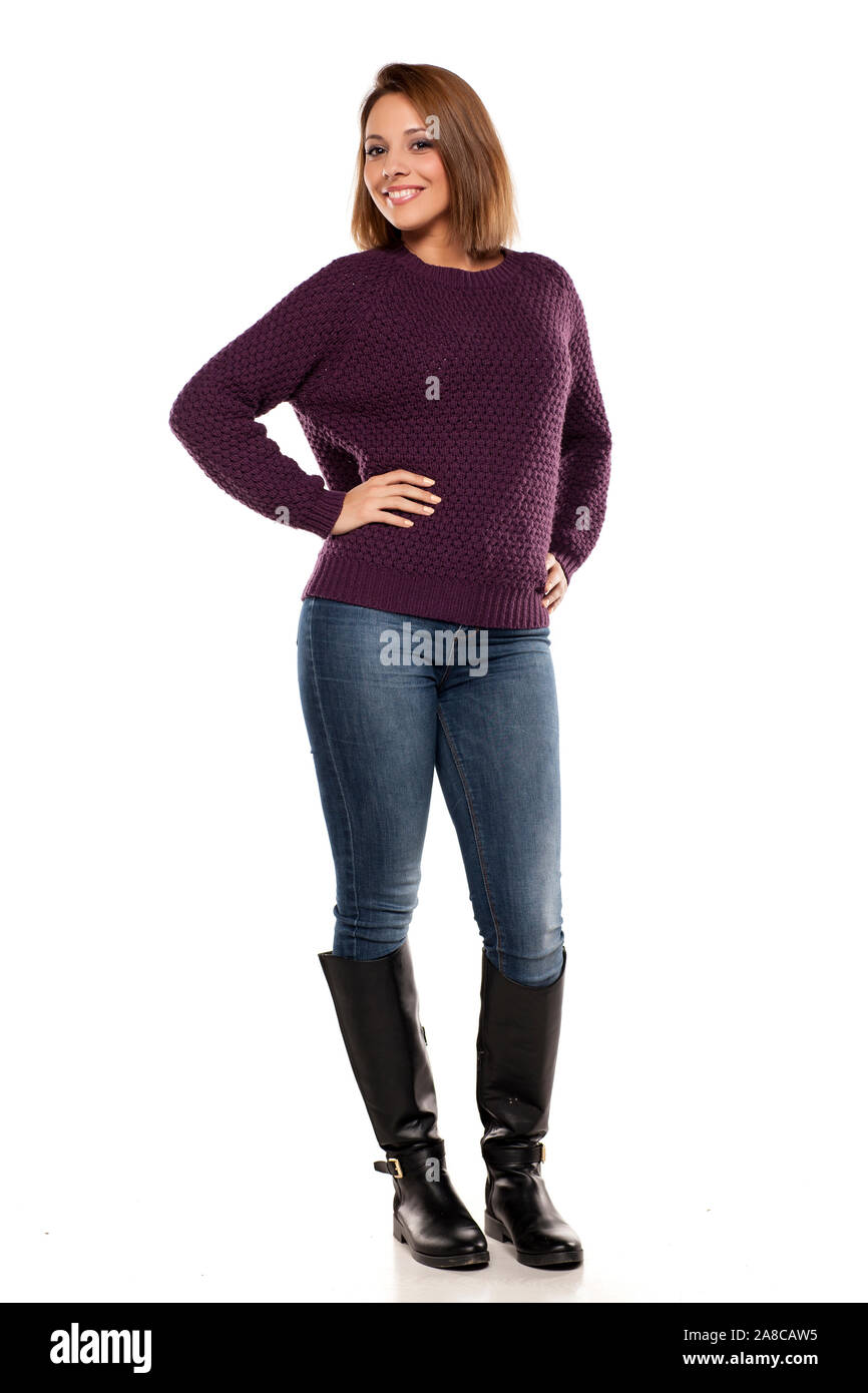 Giovane donna sorridente in un maglione viola e jeans isolato su bianco  Foto stock - Alamy