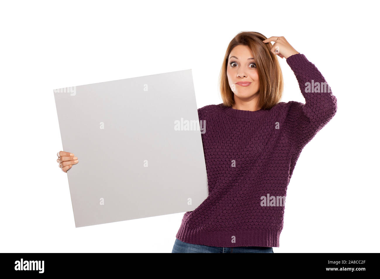 I giovani chiedono la donna in un maglione viola e jeans, tenendo una scheda vuota per la pubblicità Foto Stock