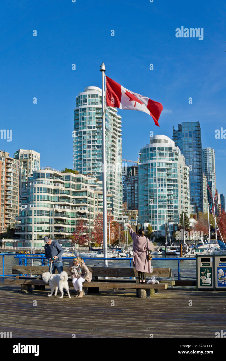 Il lungomare con la bandiera canadese su Granville Island, Vancouver, BC, Canada. Condomini e highrises su False Creek a Vancouver. Foto Stock