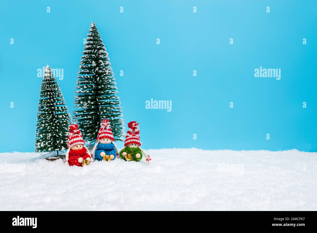 Piccole figure di Natale: bambini in maglia Maglioni holding campane. Carino il Natale bambole come una vacanza fatta a mano decorazione contro sfondo blu wit Foto Stock