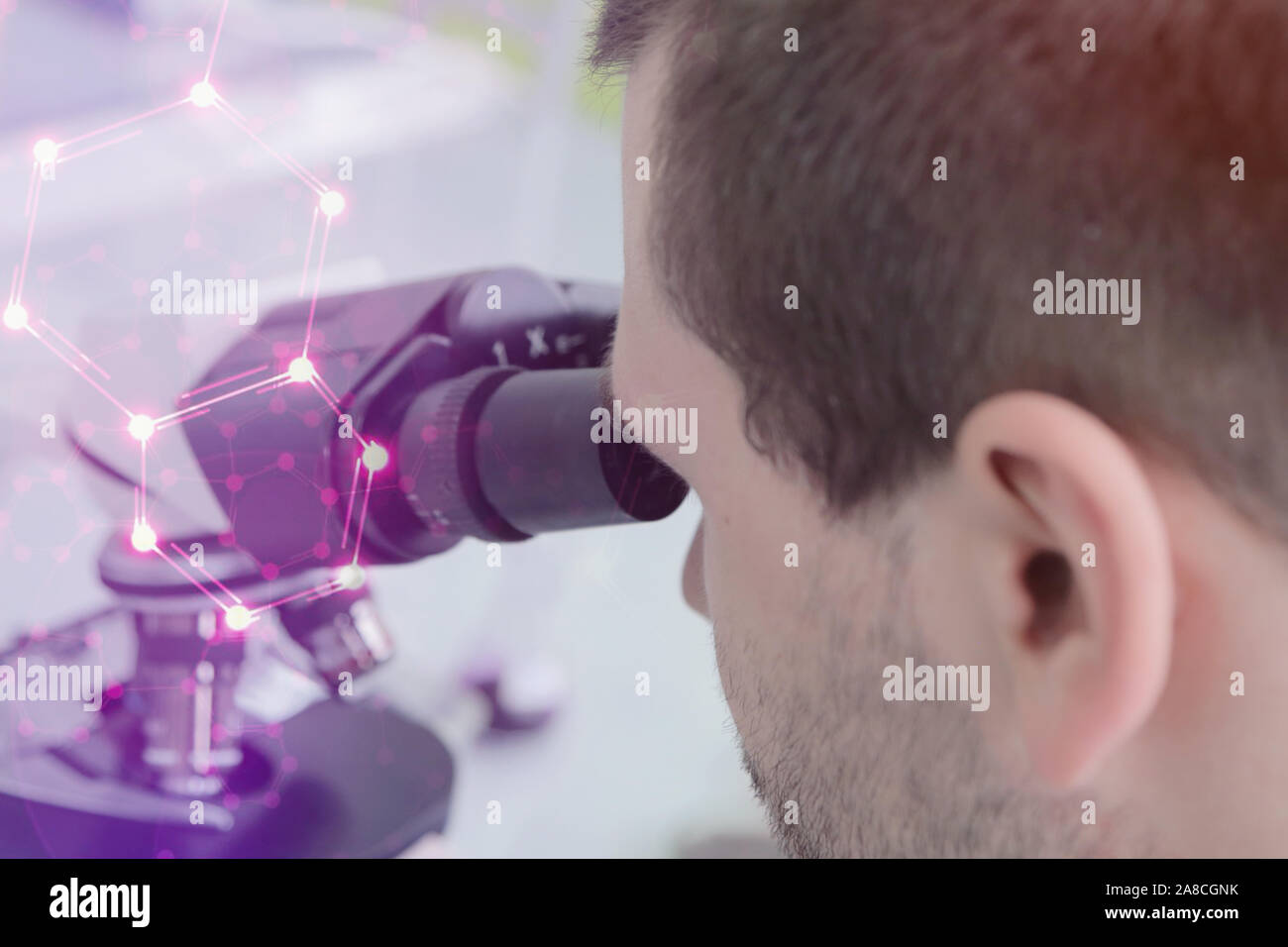 Giovane maschio maschio scienziato guardando attraverso un microscopio in un laboratorio di ricerca, l'analisi microbiologica, medicina. Foto Stock