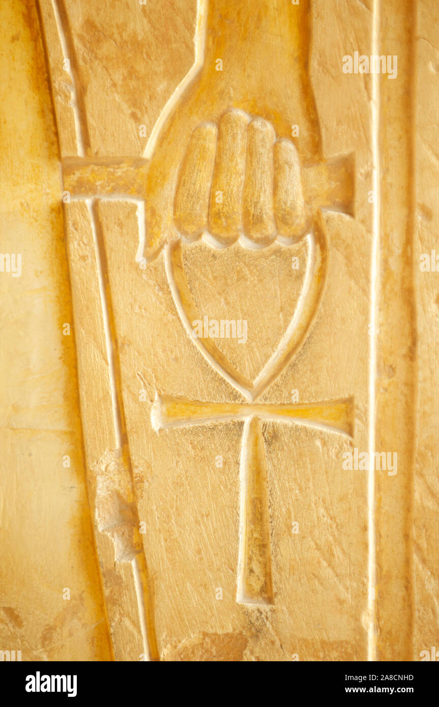 Vista ravvicinata di una mano che tiene un anh (chiave della vita) su un antico intaglio geroglifico in Eygpt Foto Stock