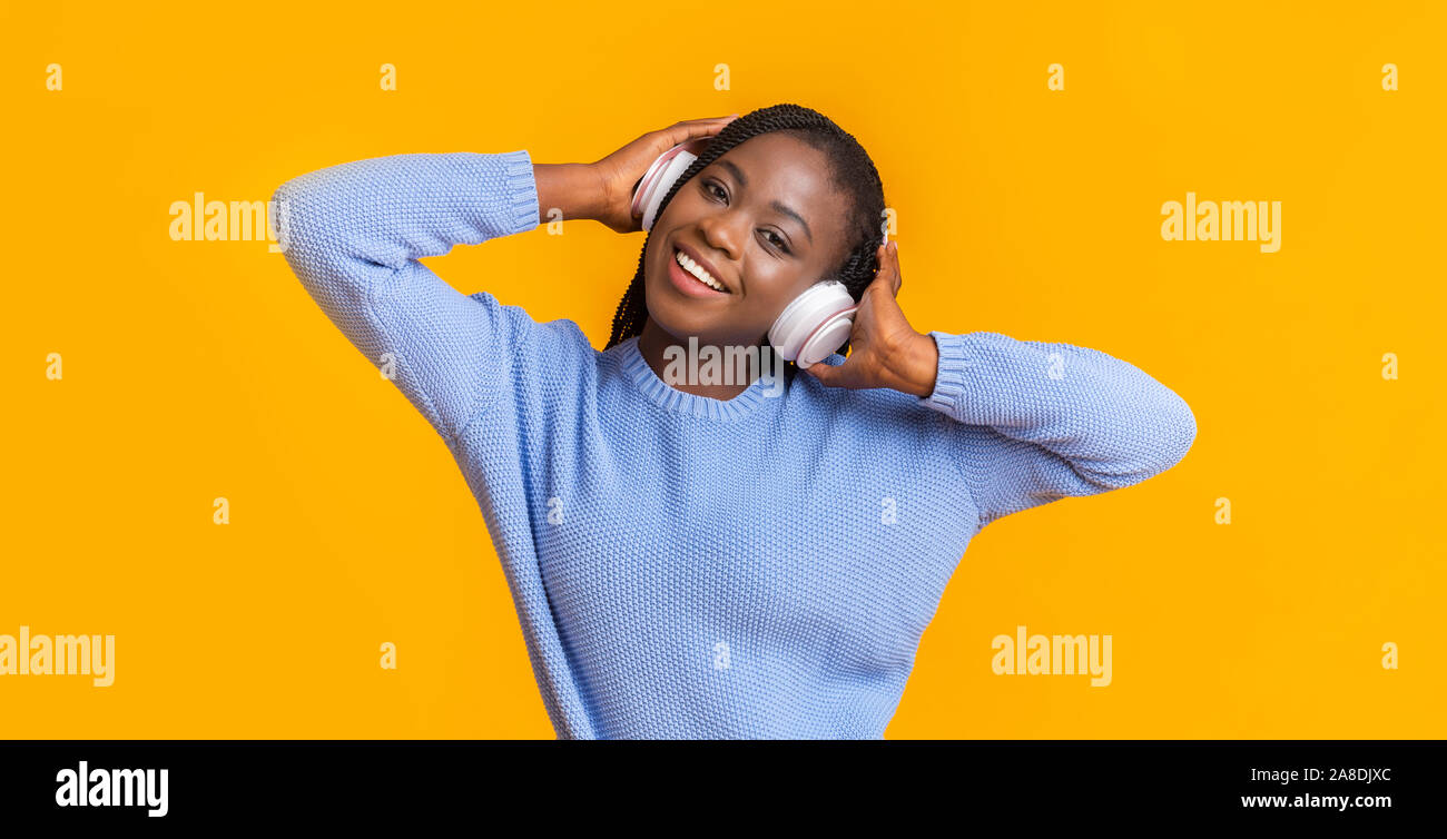 Carefree afro donna l'ascolto di musica con cuffie wireless Foto Stock