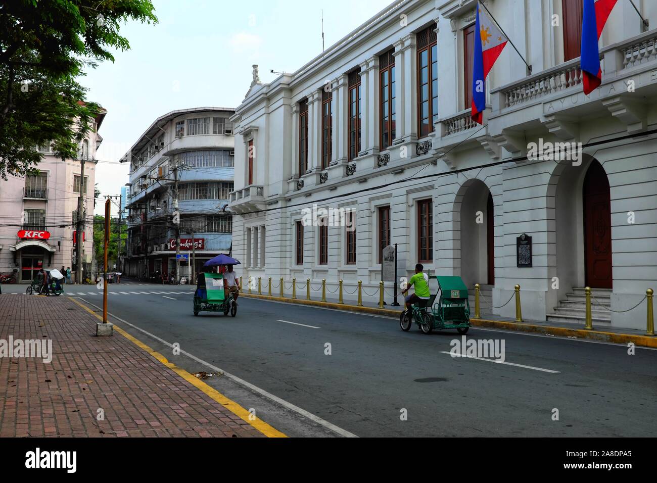 Pedicabs passano dall'Ufficio di presidenza del Tesoro in Intramuros Manila, Filippine - 18 Maggio 2019 Foto Stock