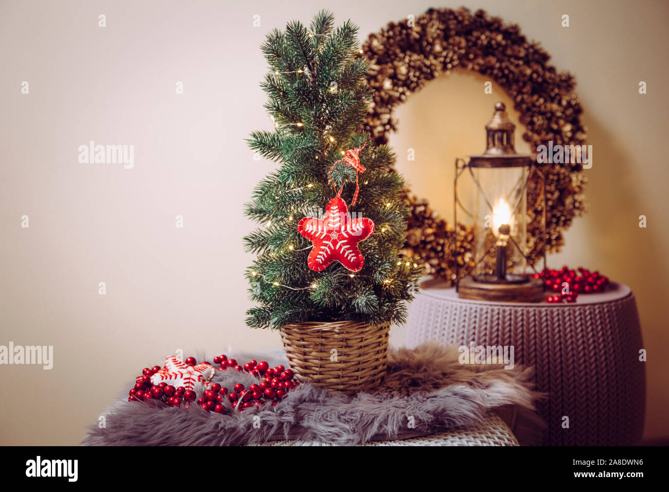 Piccolo portatile il piano portapaziente albero di Natale decorato sul tavolo, partito spie illuminate, feltro rosso ornamento del tessuto. Lampadina della luce di lanterna con cono di pino wreat Foto Stock