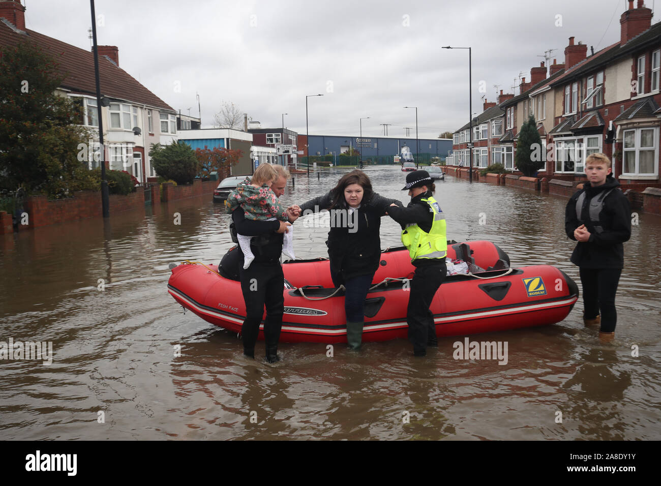 Una donna è tirato da una barca gonfiabile che è stato utilizzato per il salvataggio di residenti intrappolati dall'alluvione di Doncaster, nello Yorkshire, come parti di Inghilterra ha vissuto un mese di pioggia in 24 ore, con decine di persone soccorse o costretti ad evacuare le loro case, altri filamento durante la notte in un centro commerciale e piani di viaggio gettato nel caos. Foto Stock