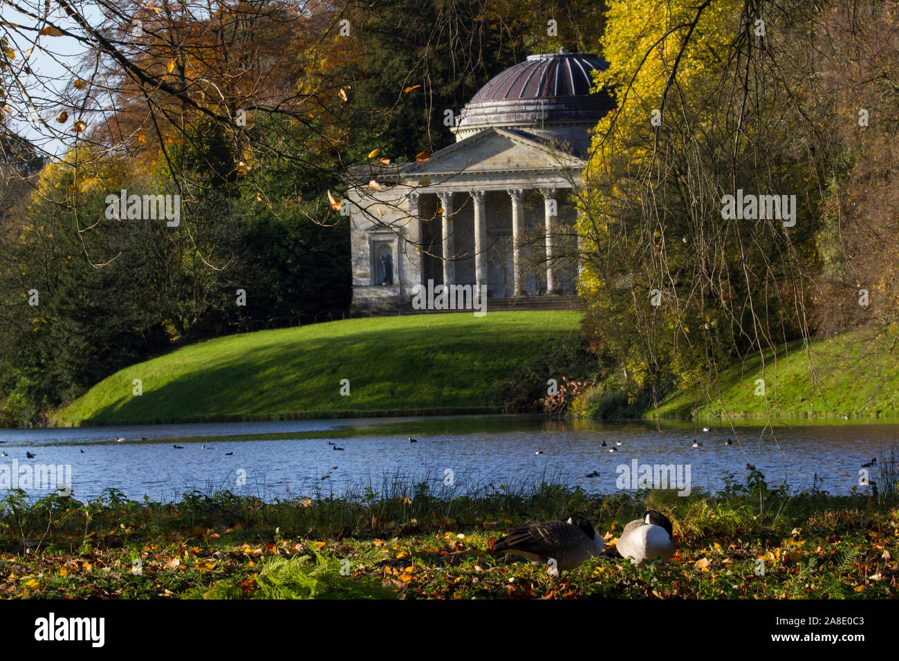 Il padiglione di pietra a Stourhead. Una meravigliosa follia in Georgian giardini paesaggistici . Il lago di fronte e i boschi alle spalle. Autunno e soleggiato. 2 Foto Stock