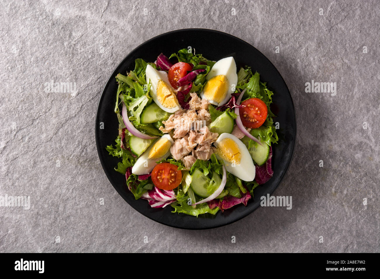 Con insalata di tonno, uova e verdure sulla piastra di nero e grigio. Vista dall'alto. Foto Stock