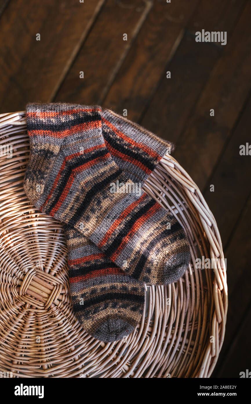 Una coppia di maglia a mano multi-colore di calze su un pad. Scuri in legno rustico sfondo. Vi preghiamo per il testo. Foto Stock