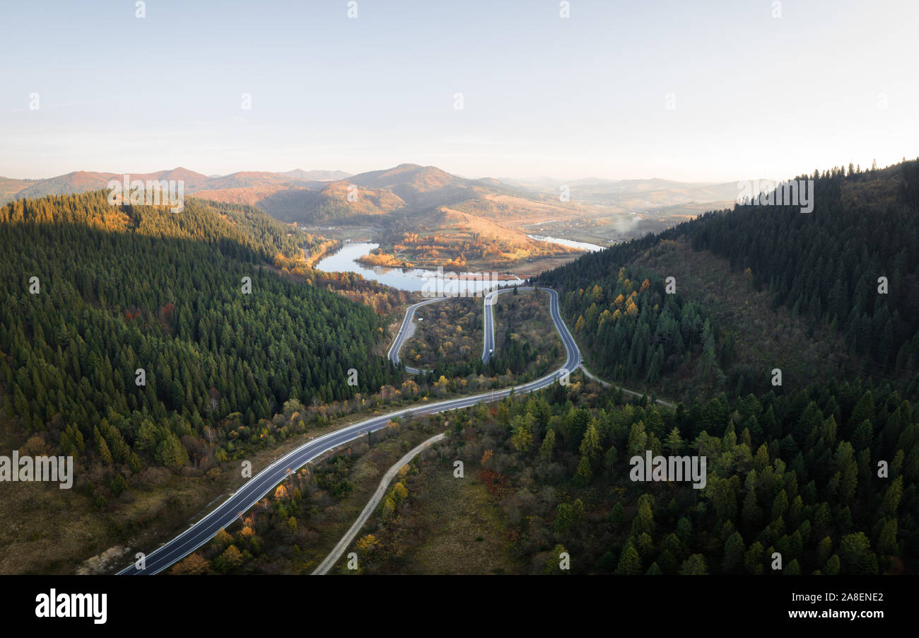 Antenna fuco vista sulle montagne di autunno con la strada di montagna serpentina, fiume e foresta. Fotografia di paesaggi Foto Stock