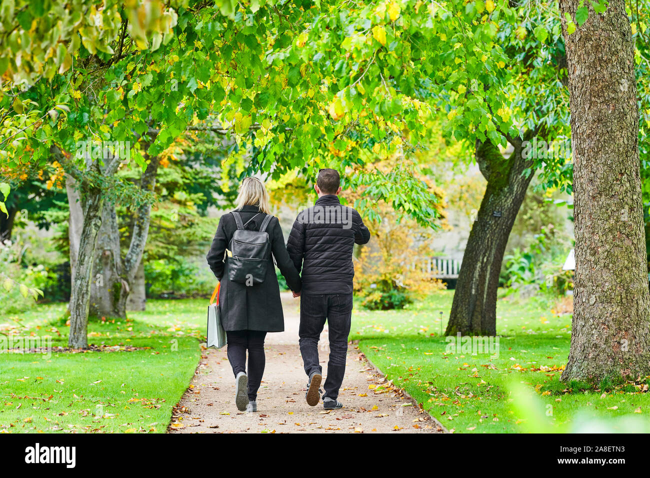 Un paio di camminare mano nella mano su un percorso durante il tardo autunno presso il giardino botanico dell'università di Oxford, Inghilterra. Foto Stock
