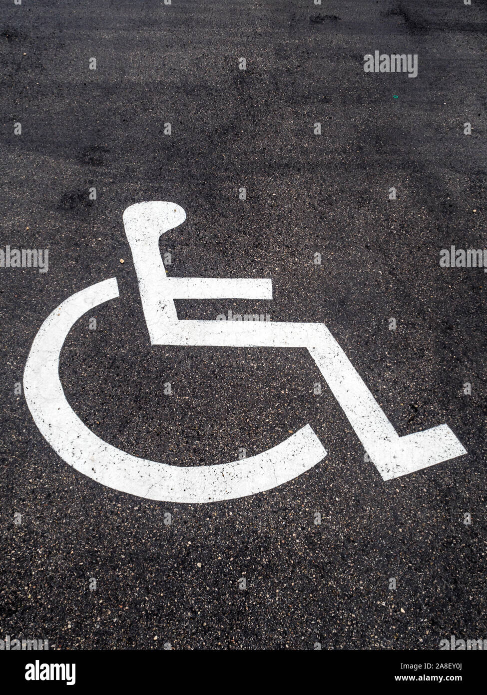Ein Rollstuhl ist auf einem Parkplatz für Behinderte angebracht. Foto Stock