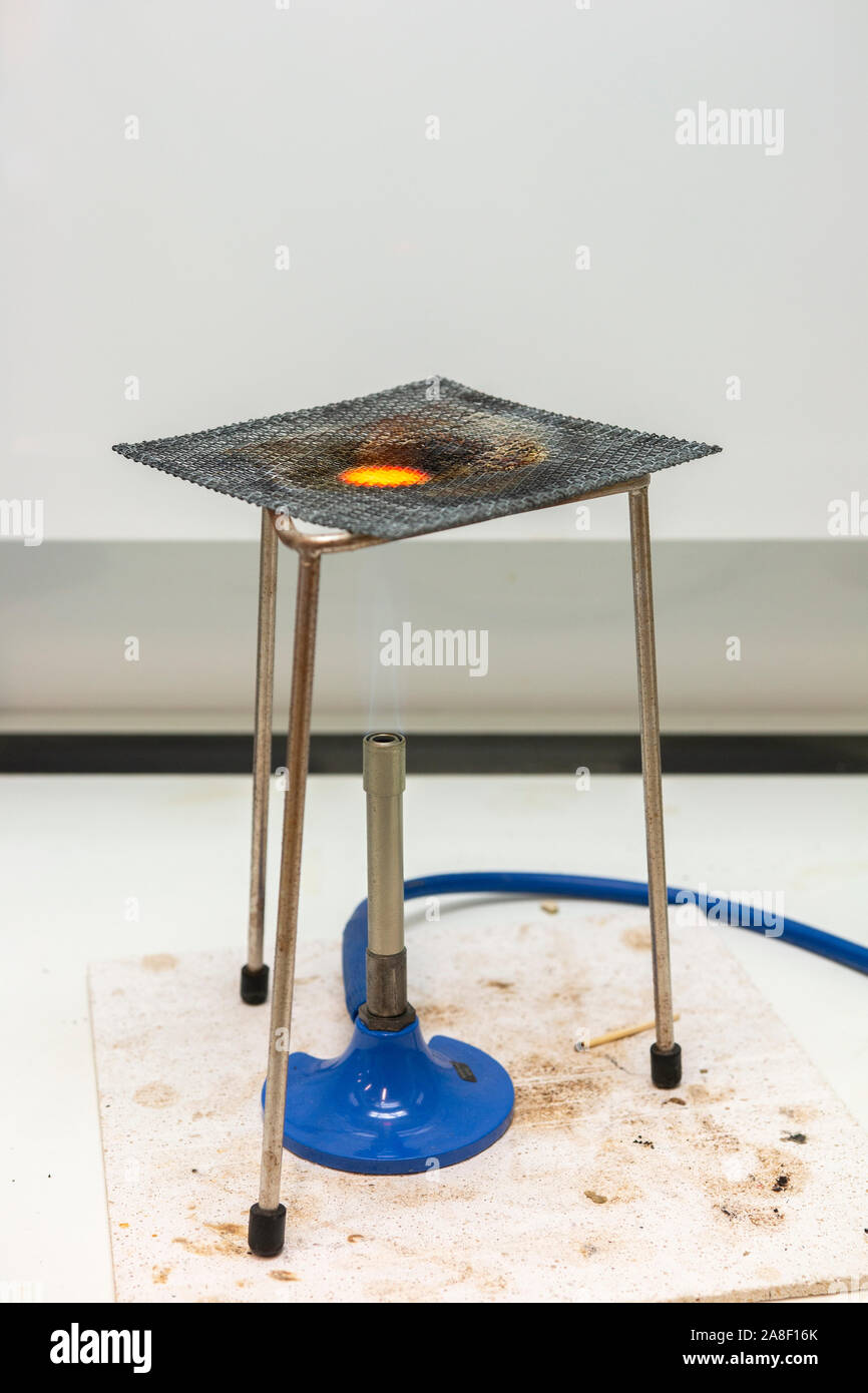 Becco Bunsen con treppiede e garza in un banco di laboratorio nel Regno Unito - illuminati per un caldo/full flame Foto Stock