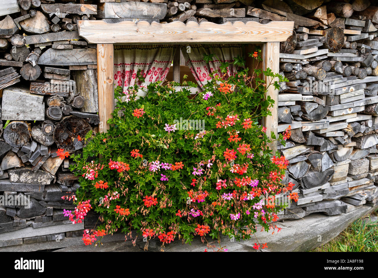 Un palo di legno, fiori e una finestra nei pressi del villaggio di Muhlbach, Austria, l'Europa. Foto Stock