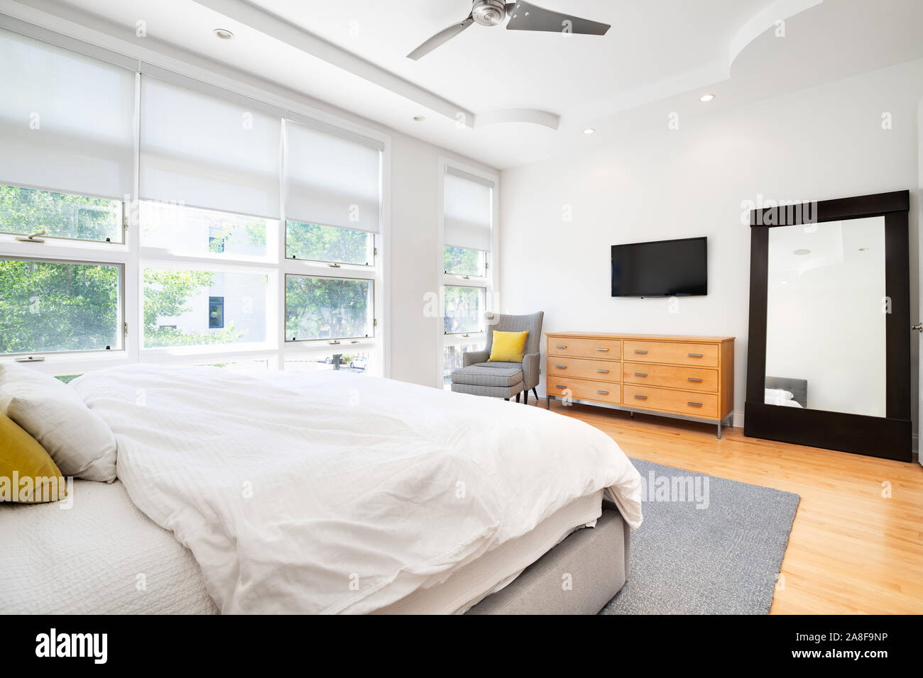 La camera da letto principale in una casa moderna con accenti di colore giallo per rendere i colori neutri pop entro la camera di grandi dimensioni. Foto Stock