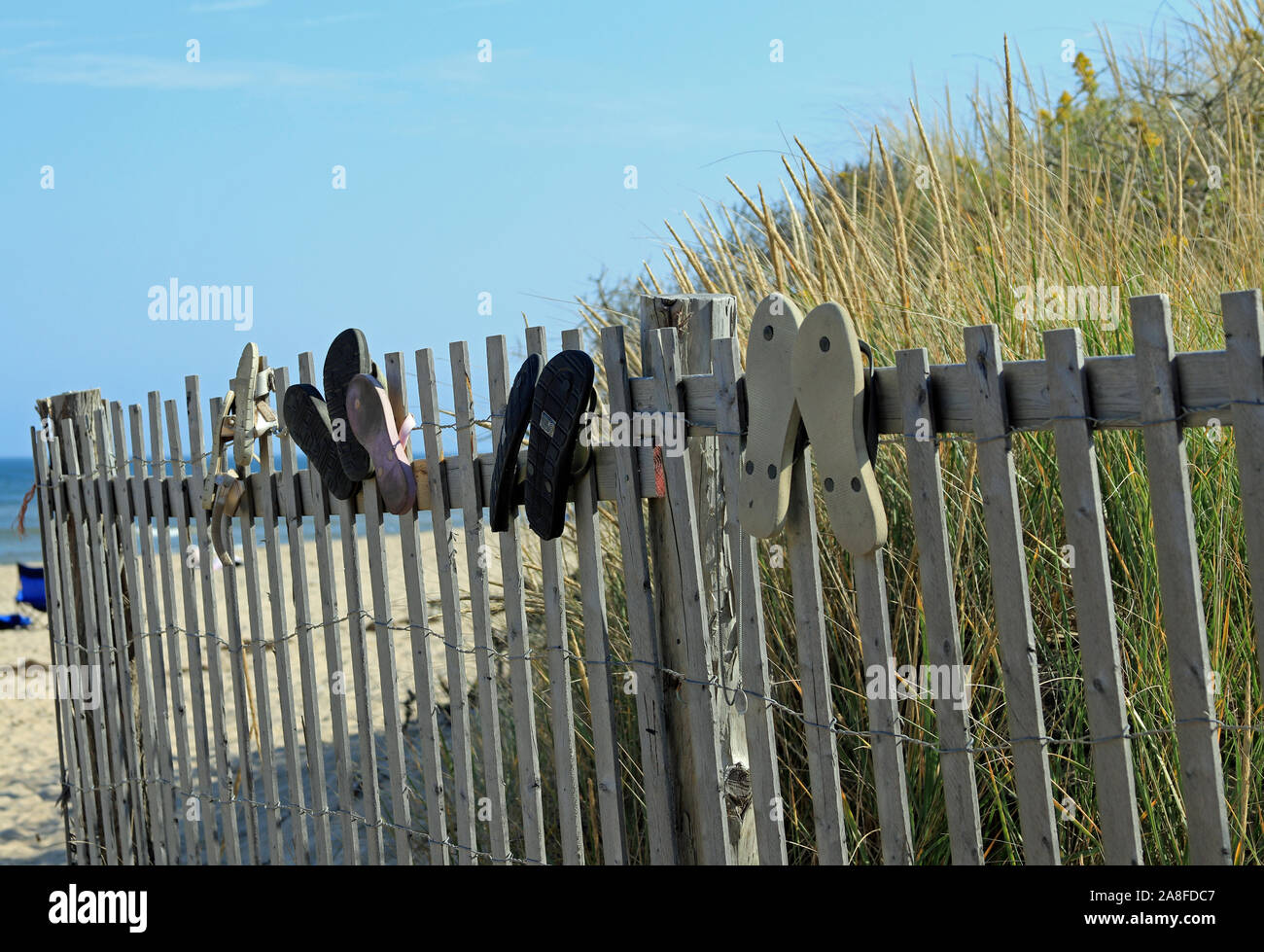 Flip-flop ad adornare un malsicuro staccionata in legno dune di protezione lungo il sentiero sabbioso ingresso alla luce Nauset Beach in Cape Cod in Eastham, Massachusetts Foto Stock