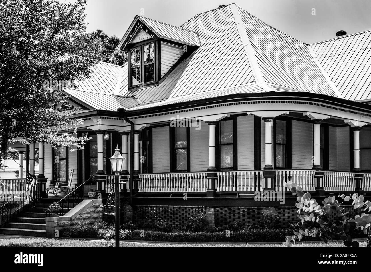 Un'impressionante residenza in stile Queen Anne con veranda avvolgente e tetto a timpani nel quartiere storico di Hattiesburg, MS, USA, B&W. Foto Stock