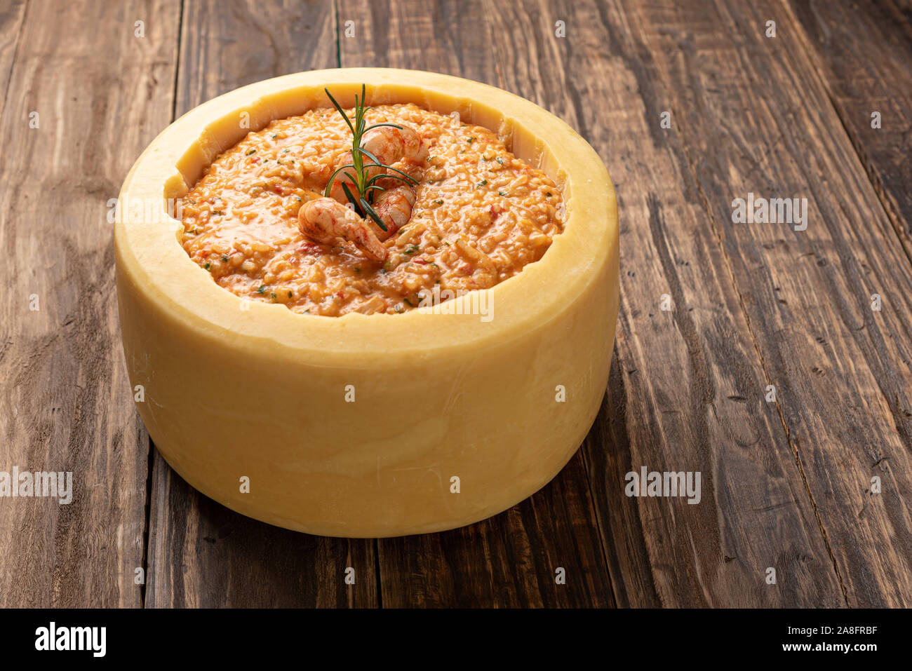 Gamberi italiana risotto all'interno di un grande formaggio parmigiano ruota su un sfondo di legno Foto Stock