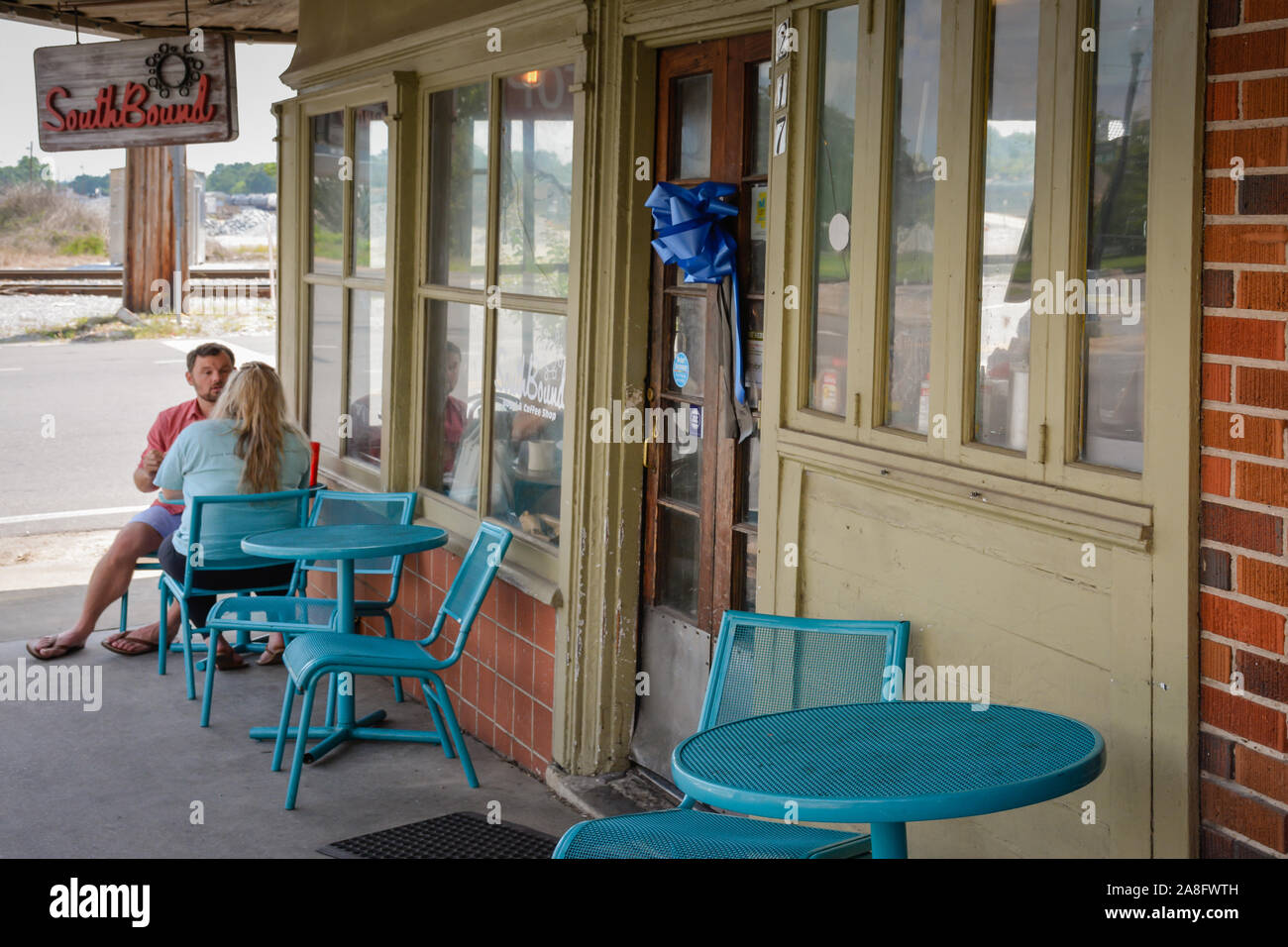 Un giovane caucasico rilassante al di fuori sul turchese bistro set del South Bound coffee shop nella piccola città America, Hattiesburg MS, STATI UNITI D'AMERICA Foto Stock