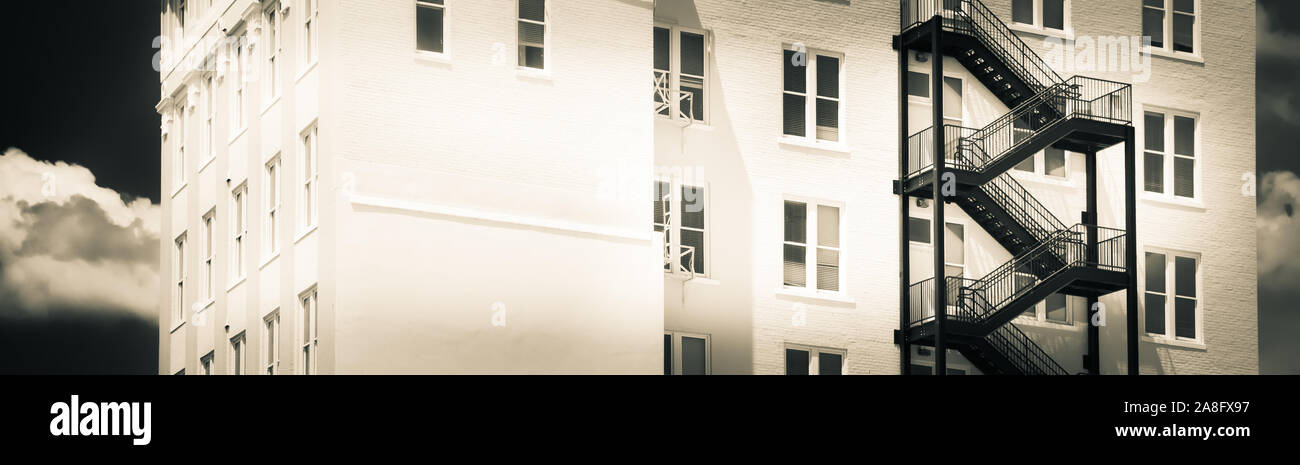 Un contrasto tra un moderno black iron fire escape su un vintage edificio di mattoni bianchi in Hattiesburg MS, STATI UNITI D'AMERICA, in un formato panoramico Foto Stock