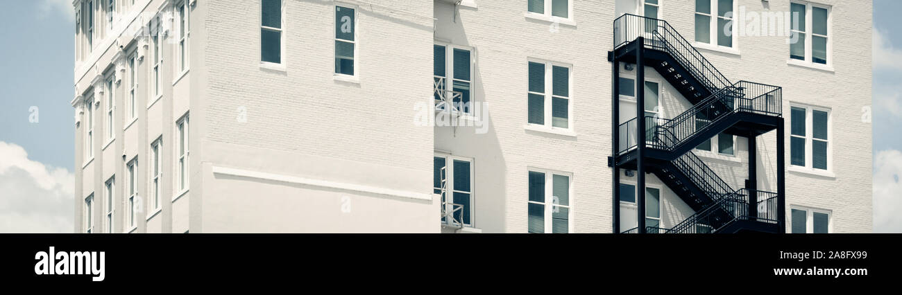 Un contrasto tra un moderno black iron fire escape su un vintage edificio di mattoni bianchi in Hattiesburg MS, STATI UNITI D'AMERICA, in un formato panoramico Foto Stock