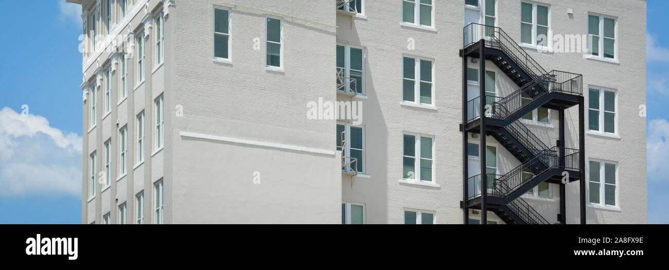 Un contrasto tra un moderno black iron fire escape su un vintage edificio di mattoni bianchi in Hattiesburg MS, STATI UNITI D'AMERICA, in un formato panoramico Foto Stock