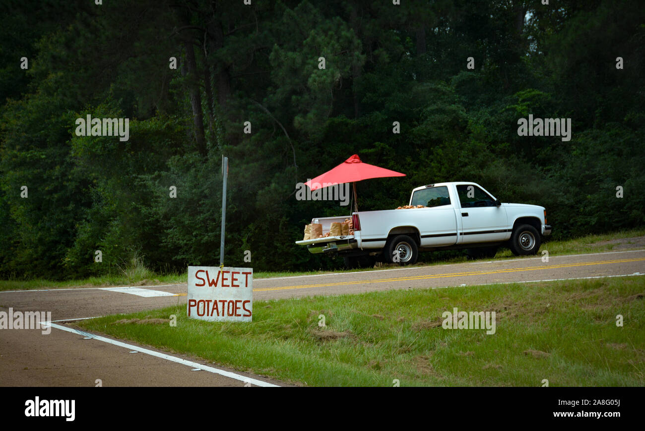 Un fornitore di produrre in un carrello di prelievo sul lato della strada con un segno di patate dolci nelle zone rurali del sud del Mississippi, STATI UNITI D'AMERICA, Foto Stock