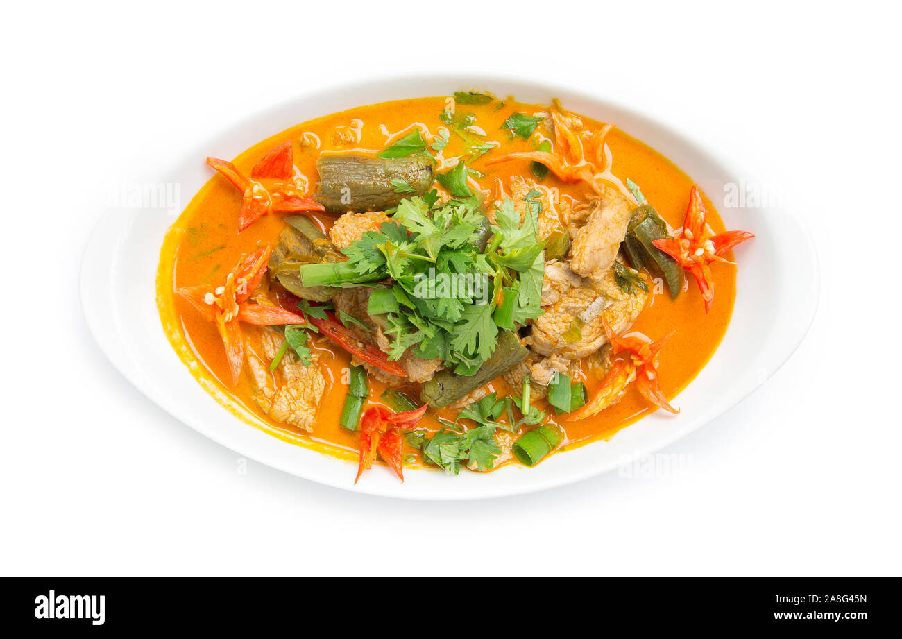 Red Curry maiale con latte di cocco (Kang phed muu) Thaifood curry stile spisy guarnita con coriandolo decorare scolpiti chili vista dall'alto isolato su bianco bac Foto Stock