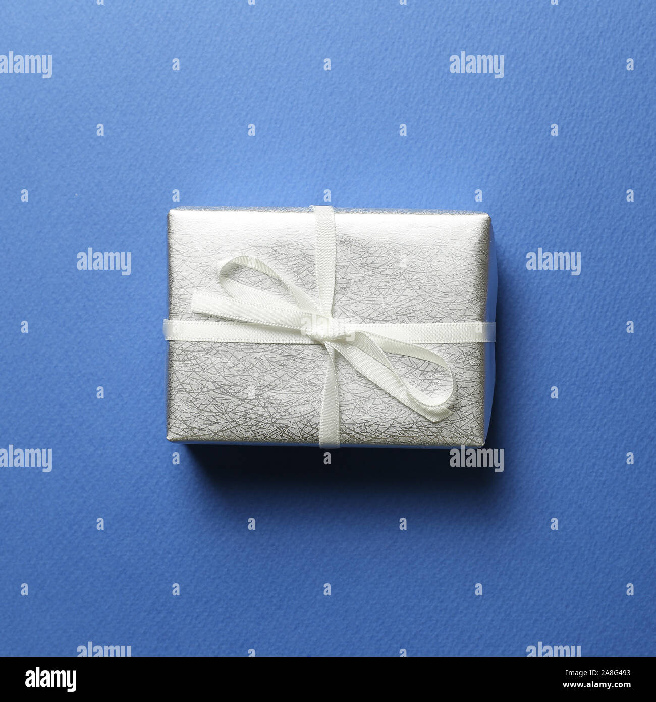 Argento Confezione regalo su sfondo blu. Il Natale o il concetto di compleanno Foto Stock