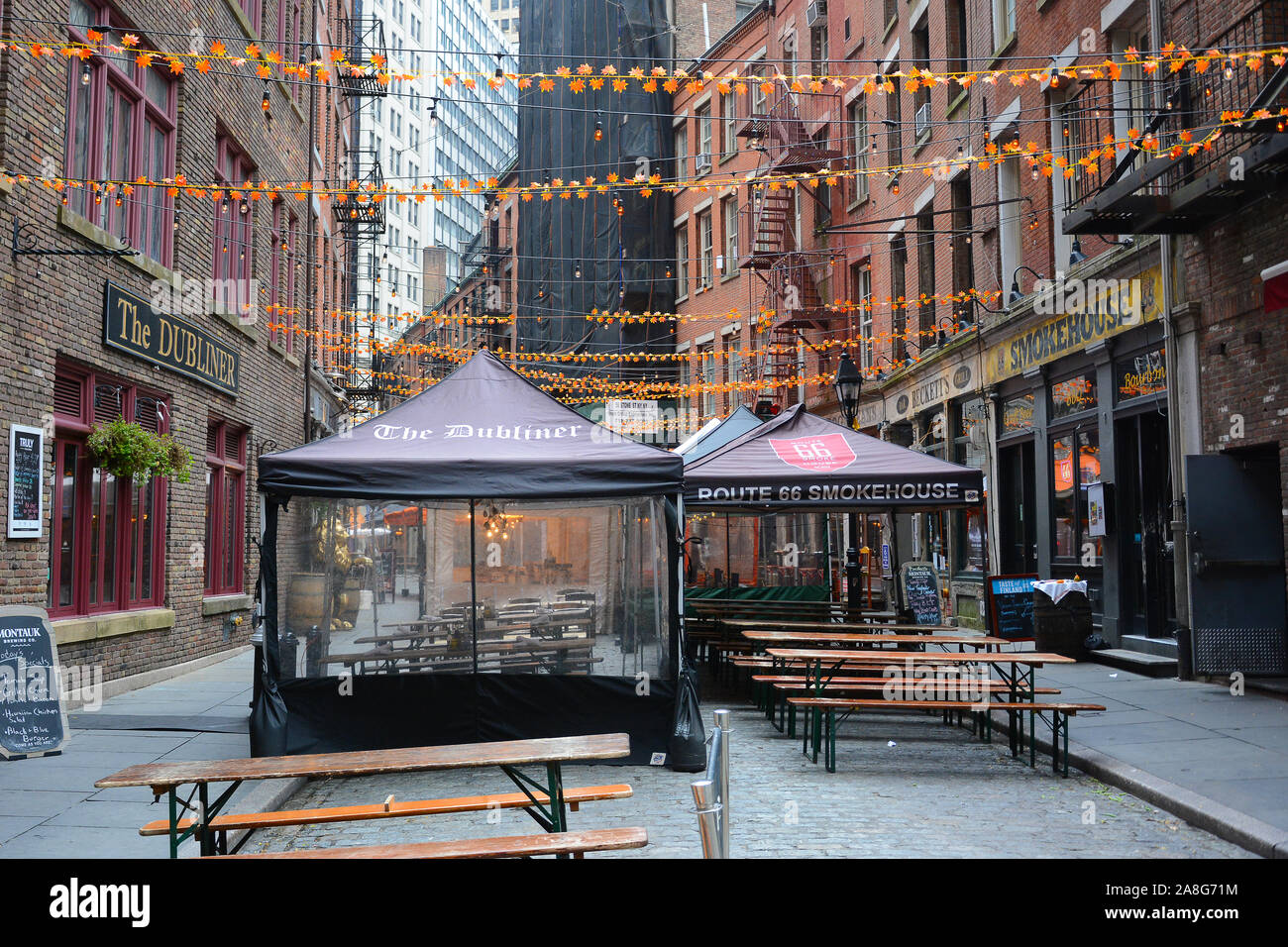 NEW YORK, NY - 05 NOV 2019: Stone Street Ristoranti impostare tende in una stretta strada di ciottoli nel cuore del quartiere finanziario. Foto Stock