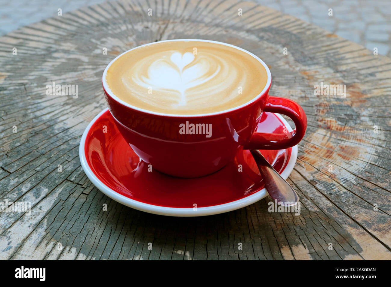 Hot Cappuccino caffè nella tazza rossa servita sul ceppo di albero tabella Foto Stock