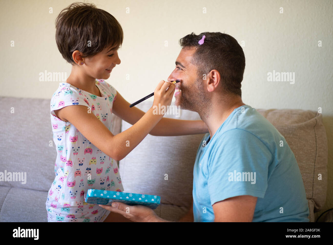 Poco carino figlia facendo il make-up per suo padre Foto Stock