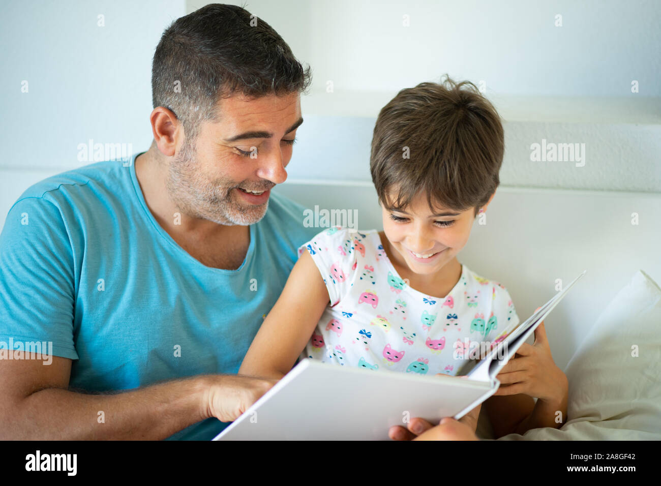 Medio-età padre con i suoi otto anni figlia utilizzando digitale compressa nella camera da letto. Foto Stock