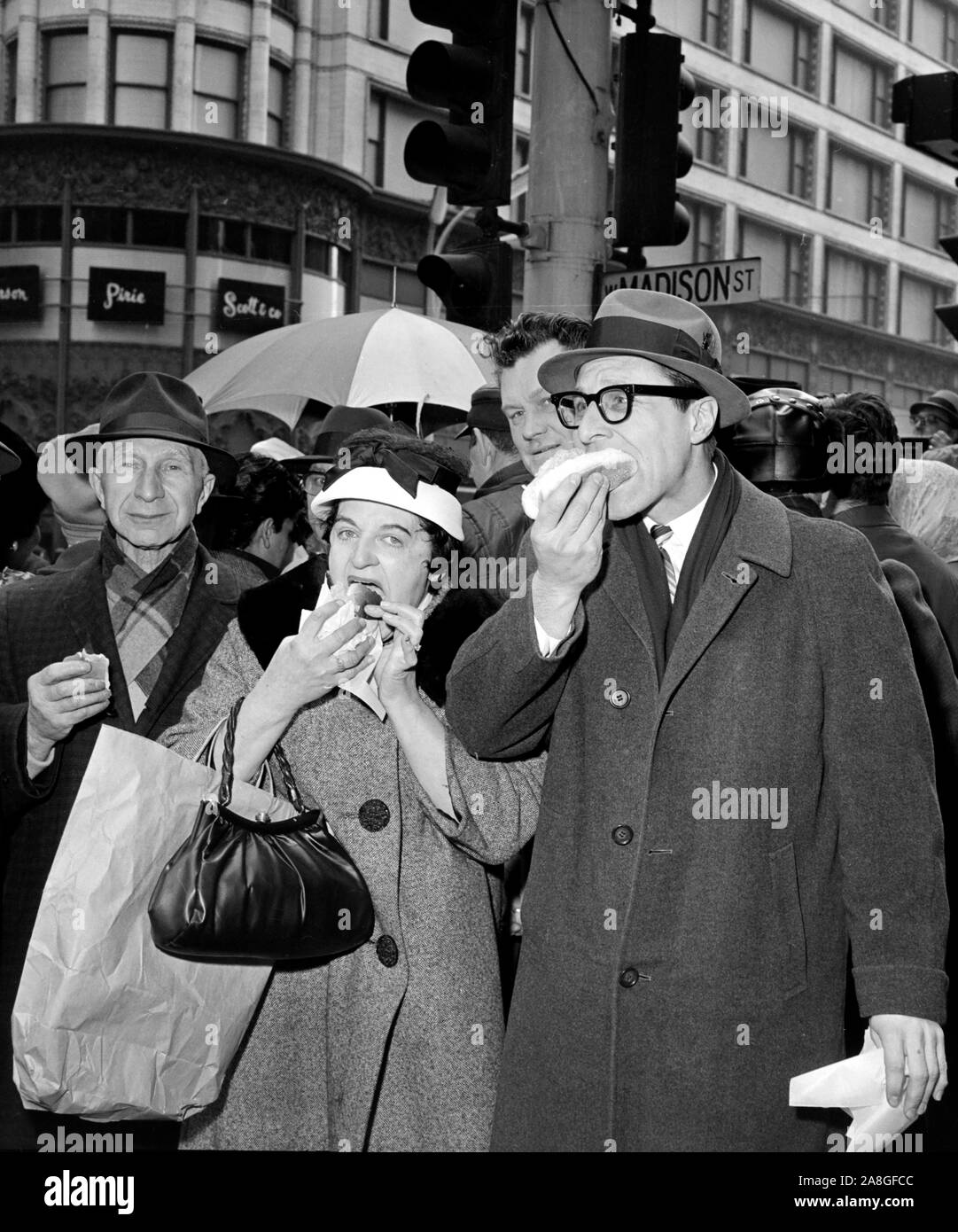 Un uomo e una donna godere un hot dog durante un Kraut Nazionale e dal Frankfurter settimana promozione su Chicago di State Street, nel gennaio 1964. Foto Stock