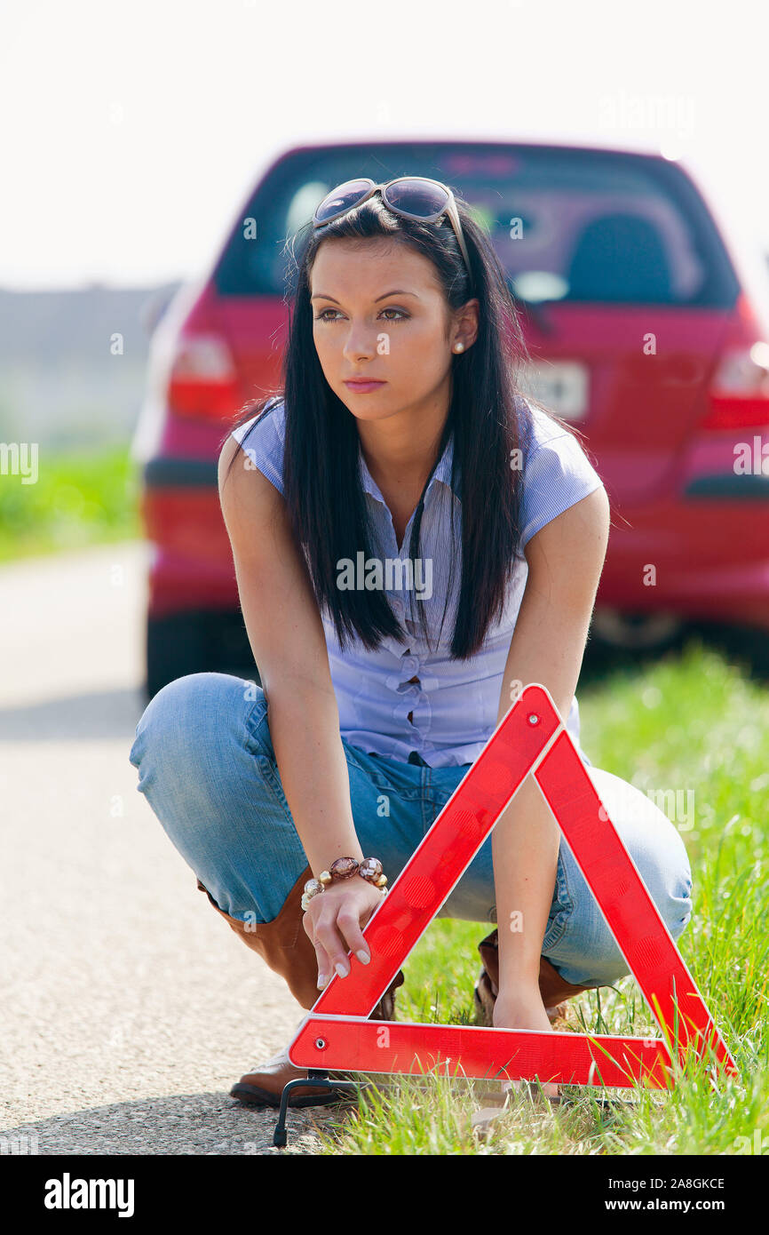Junge Frau Mit einem Warndreieck bei einer Autopanne, 25, 30, Jahre, signor: Sì Foto Stock