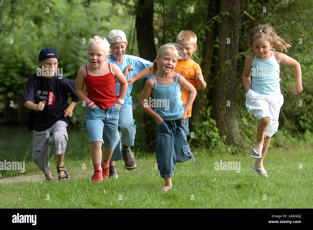 Kinder laufen über eine Wiese im Park, 6 Kinder, Jungs und Mädchen, signor:Sì Foto Stock