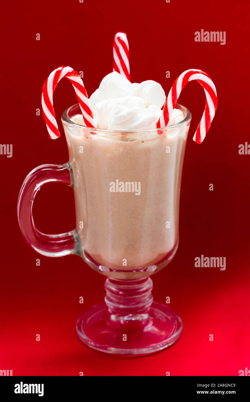 Un bicchiere di cioccolata calda con marshmallows e Natale candy su uno sfondo di colore rosso. Bevande di Natale concetto. Foto Stock