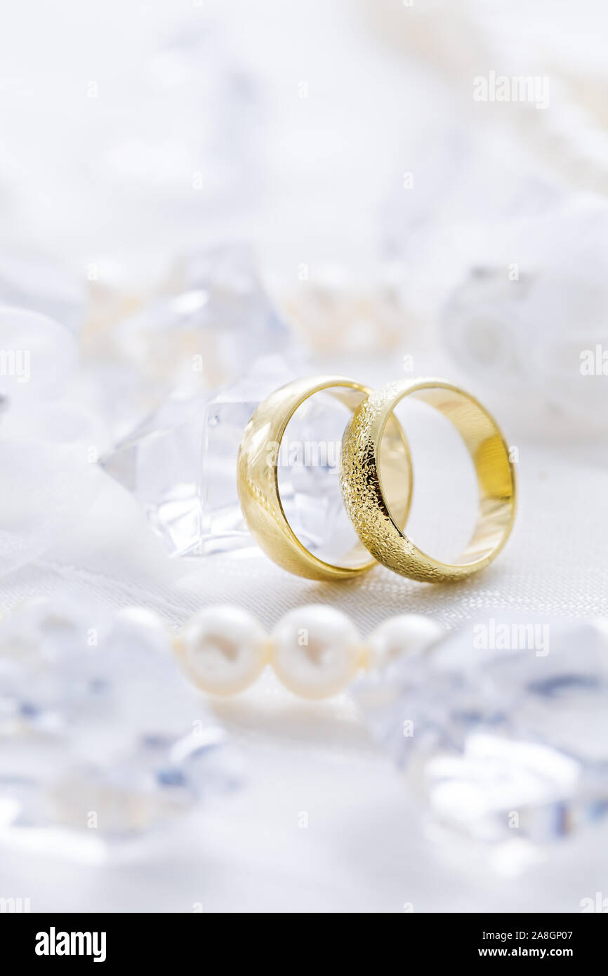 Due anelli d oro con collana di perle e su sfondo bianco come simbolo dell amore e del matrimonio Foto Stock