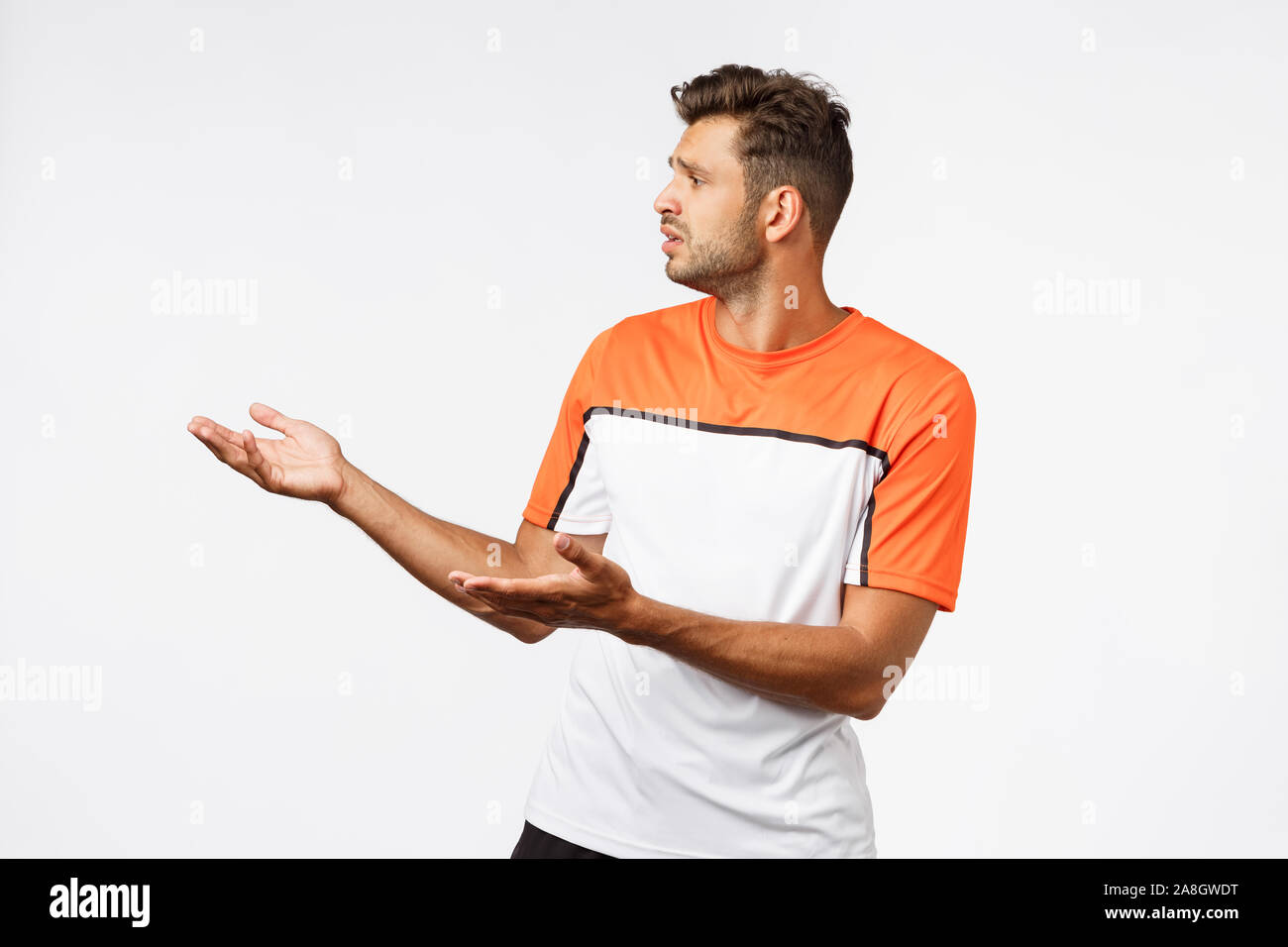 Deluso triste barbuto maschio maschile del trainer in sport t-shirt, guardando sconvolto sinistra alzando le mani in sgomento e antipatia, giudicando qualcosa di male Foto Stock