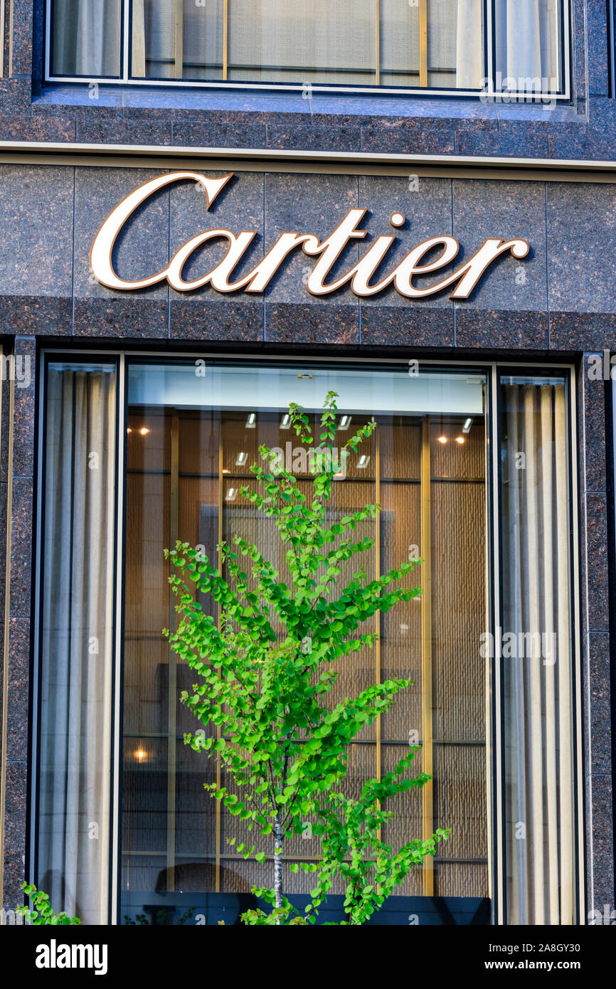 La boutique Cartier Tokyo Ginza la costruzione di dettaglio. Parte anteriore della finestra di visualizzazione con struttura ad albero di primavera in primo piano nella parte anteriore e di Cartier logo di cui sopra. Foto Stock