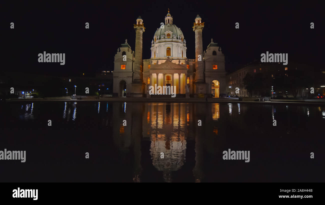 Un ultra wide night shot di san Carlo Chiesa riflessa in una piscina a vienna Foto Stock