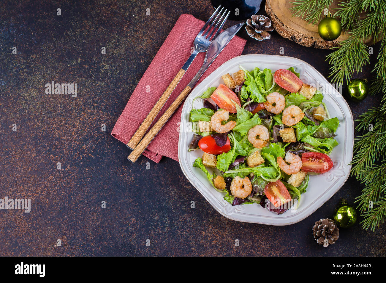 Fresca insalata caesar con gamberi sulla piastra bianca pietra scura sullo sfondo della tabella con la festa di natale decorazione. Healhty Food Snack concetto. Vista superiore della COP Foto Stock