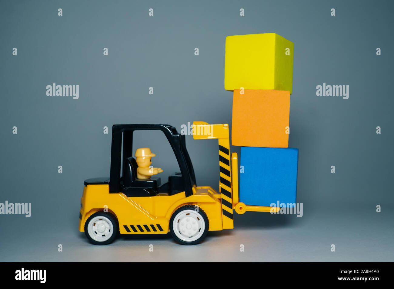 Giallo carrello carico giocattolo cubetti di colore. Giocattoli per bambini. Piccolo carrello caricatore e tre cubi Foto Stock