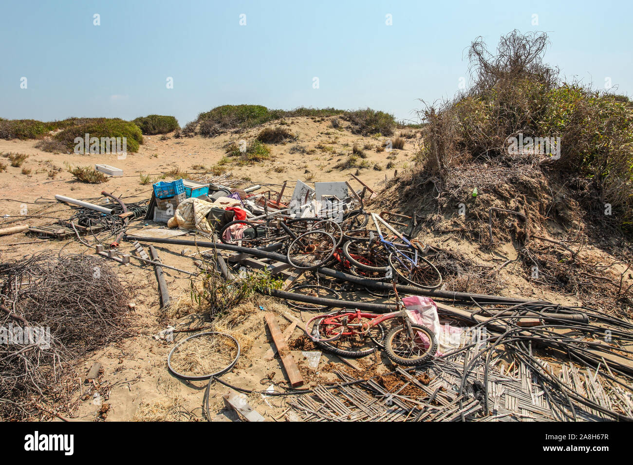 Pila di vecchio arrugginito scartato biciclette posa sulla sabbia nel sole forte. Tutti i marchi / loghi rimosso. Foto Stock