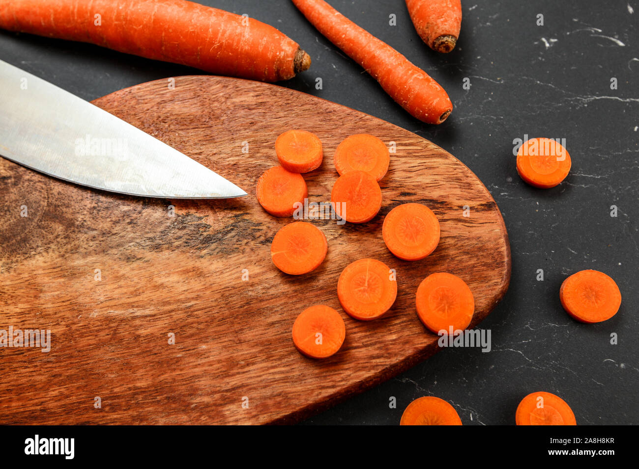 Le carote di legno e spacco nero scheda di lavoro, alcuni di essi tagliati a cerchi con il Coltello per cuoco, vista da sopra Foto Stock
