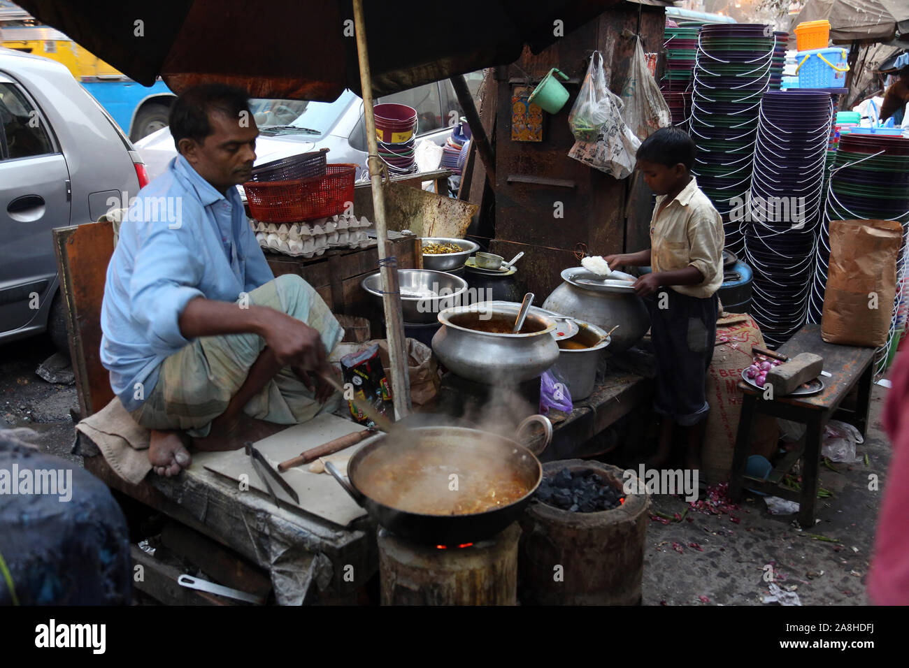 Padre e figlio si prepara semplice cibo di strada all'aperto in Kolkata Foto Stock
