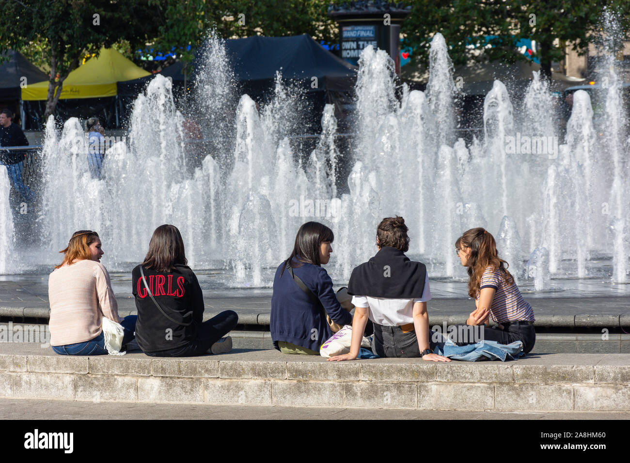 Le ragazze adolescenti seduto da Fontana di Piccadilly Gardens nel centro della città, Manchester, Greater Manchester, Inghilterra, Regno Unito Foto Stock