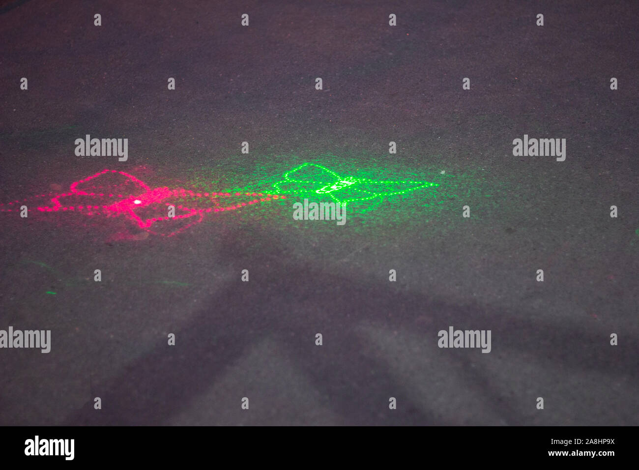 Il raggio laser sul asfalto butterfly pattern. verde e rosa. sfondo spazio di copia Foto Stock